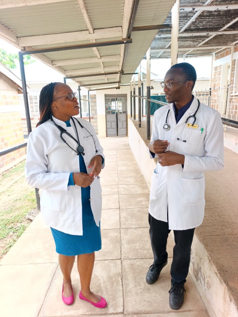Two clinicians talking in a covered walkway at the hospital