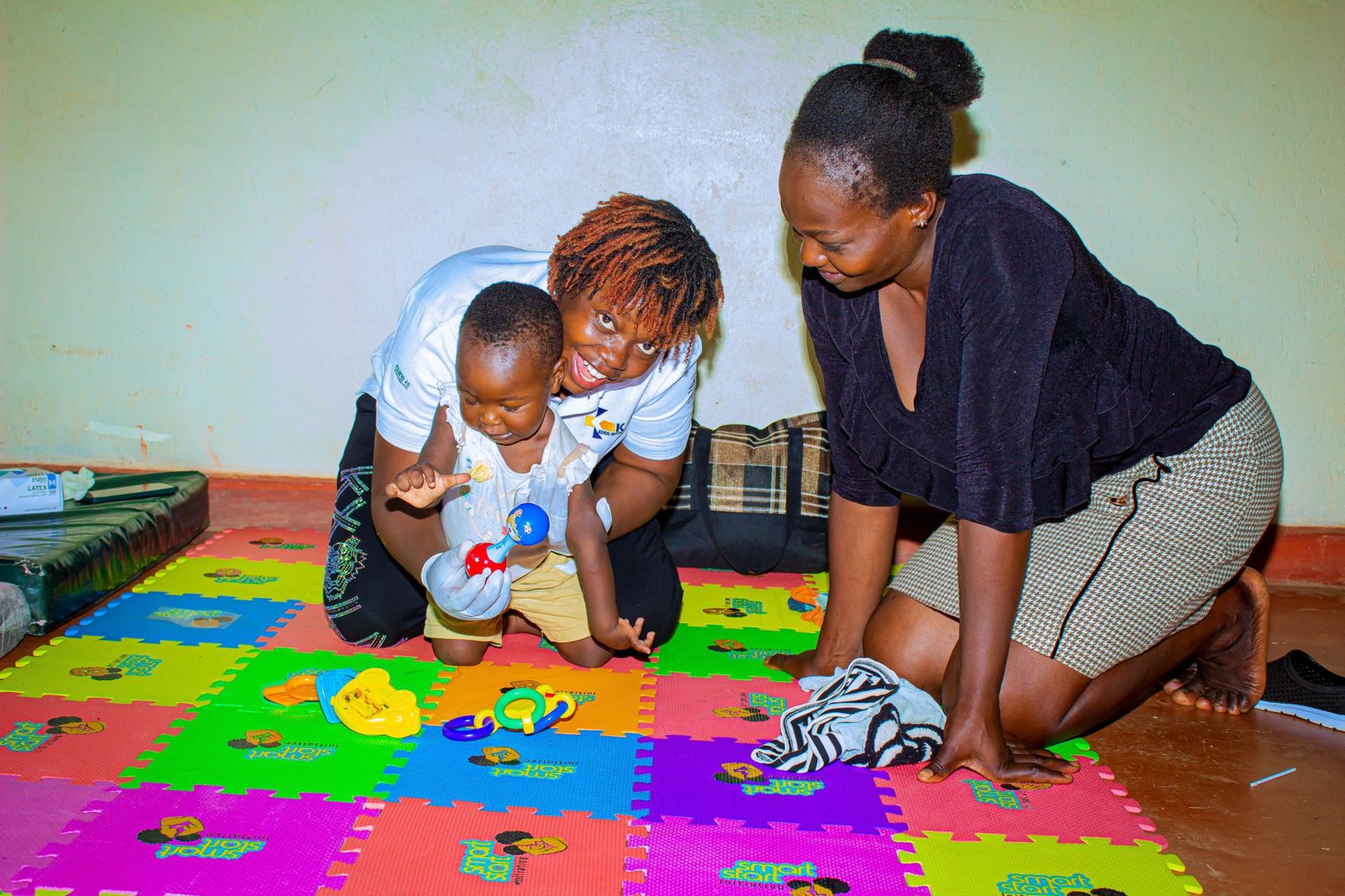A therapist working with a child and parent on a play mat